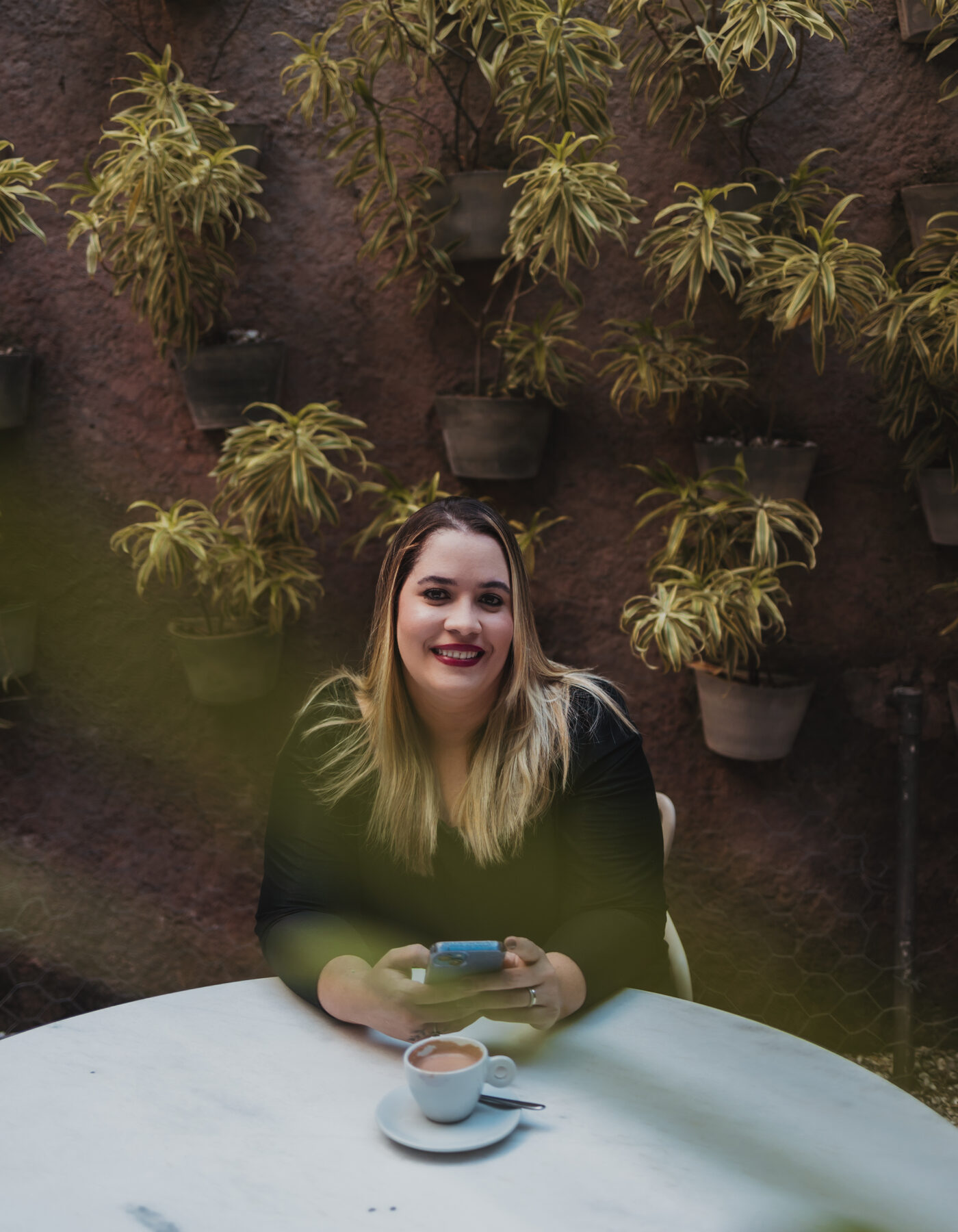 Anna sorrindo entre plantas